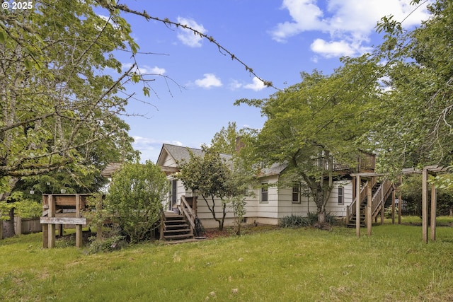 back of house with stairs, a deck, and a yard
