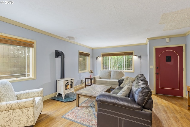 living area featuring light wood-style flooring, a wood stove, ornamental molding, baseboards, and a textured ceiling