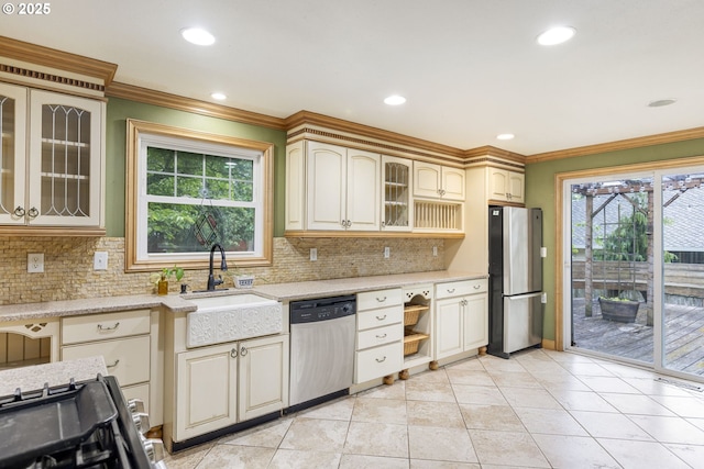 kitchen with appliances with stainless steel finishes, a sink, ornamental molding, backsplash, and glass insert cabinets