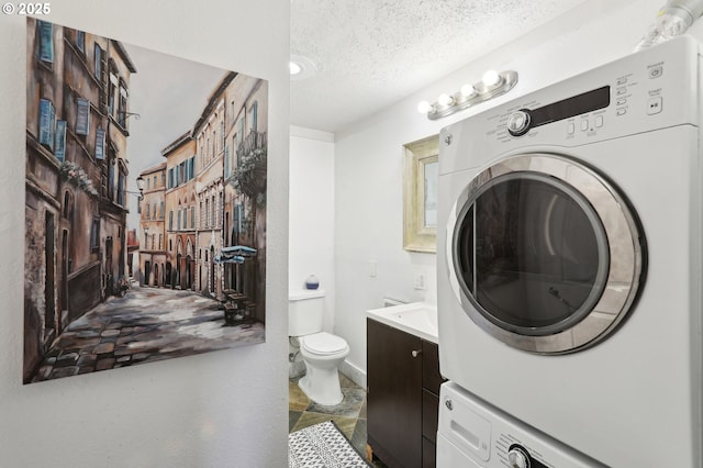 bathroom with vanity, stacked washer and dryer, toilet, and a textured ceiling