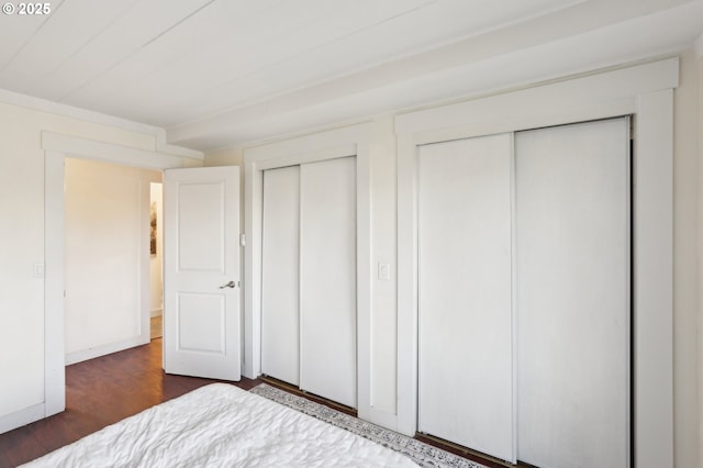 unfurnished bedroom featuring multiple closets and dark wood-type flooring