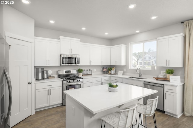 5603 Edward Ct SE, Albany, OR 97322 - kitchen with stainless steel appliances, a kitchen bar, white cabinets, dark wood-type flooring, and recessed lighting