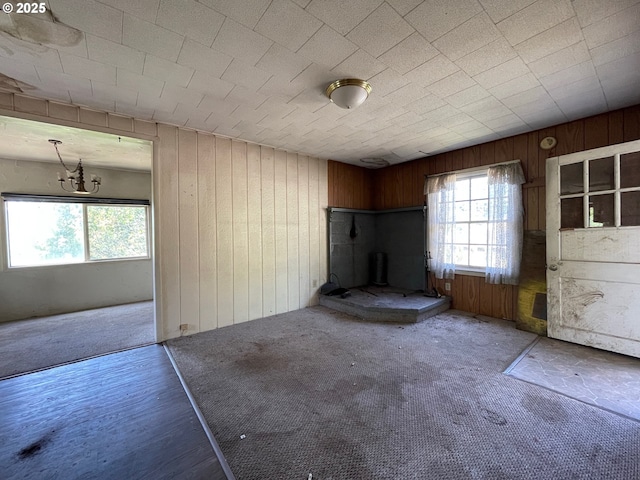 91456 State Rd, Coquille, OR 97423 - unfurnished living room featuring wood walls, healthy amount of natural light, carpet floors, and a chandelier