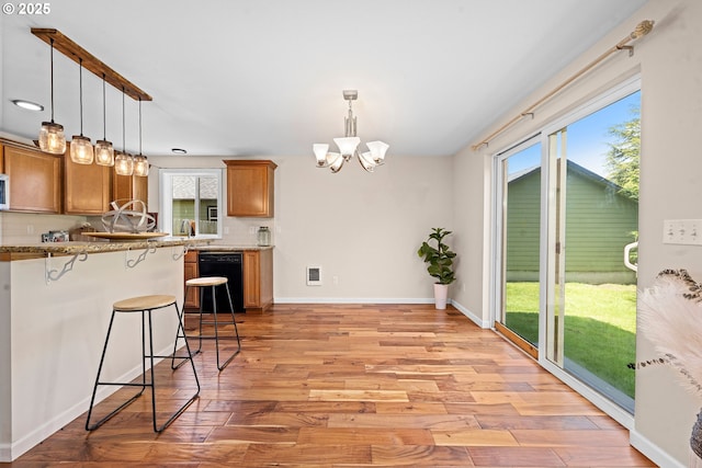 1225 3rd Ave, Hammond, OR 97121 - kitchen with a chandelier, black dishwasher, brown cabinetry, a kitchen breakfast bar, and light wood finished floors