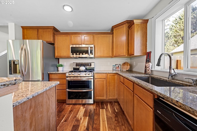 1225 3rd Ave, Hammond, OR 97121 - kitchen featuring appliances with stainless steel finishes, a sink, dark wood-type flooring, light stone countertops, and tasteful backsplash