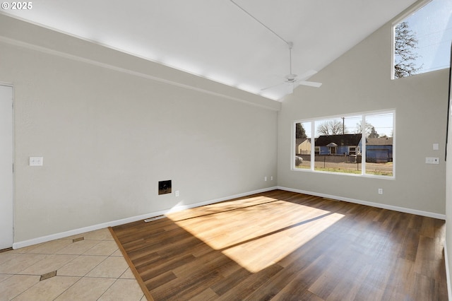 empty room featuring hardwood / wood-style flooring, high vaulted ceiling, and ceiling fan