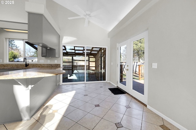 kitchen with plenty of natural light, light tile patterned floors, light stone counters, and french doors