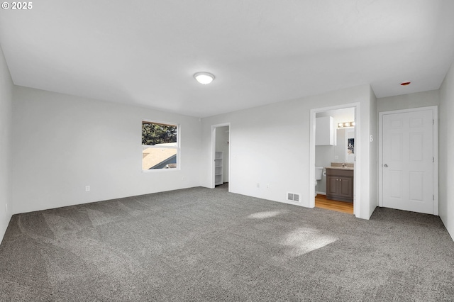 unfurnished bedroom featuring connected bathroom, carpet floors, and sink