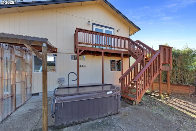 rear view of property featuring a wooden deck, a hot tub, and a patio area