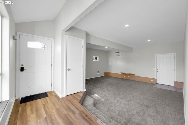 carpeted foyer entrance with lofted ceiling and a wall mounted AC