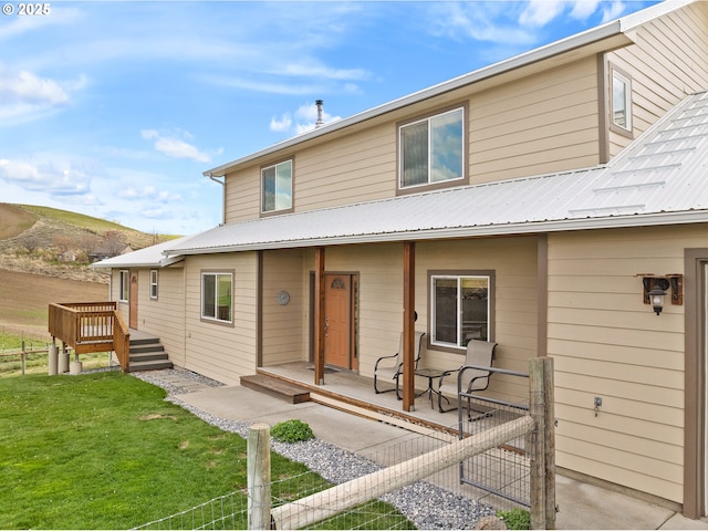 view of front facade featuring a front yard, fence, and metal roof