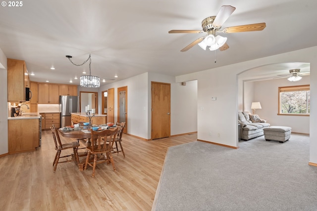 dining area featuring recessed lighting, light wood finished floors, ceiling fan with notable chandelier, and baseboards