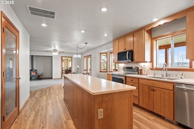 kitchen with light wood-style flooring, a center island, visible vents, stainless steel appliances, and a sink
