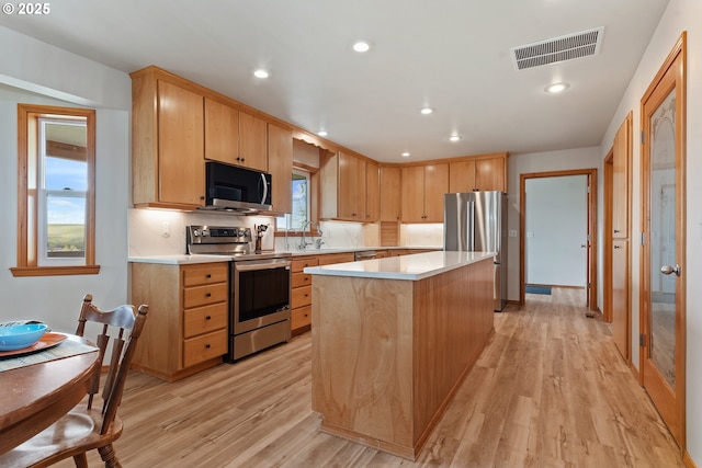 kitchen with light wood finished floors, light countertops, visible vents, and stainless steel appliances