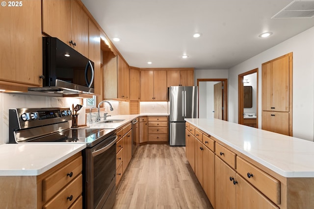 kitchen with visible vents, a center island, a sink, light wood-type flooring, and appliances with stainless steel finishes