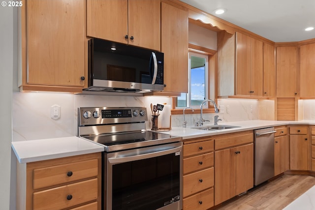 kitchen featuring a sink, light countertops, appliances with stainless steel finishes, light wood-style floors, and decorative backsplash