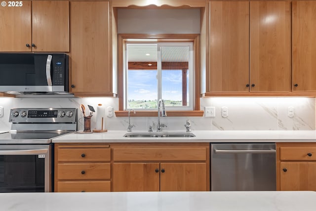 kitchen with stainless steel appliances, light countertops, a sink, and decorative backsplash