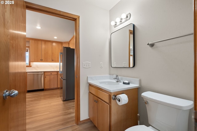 half bathroom with toilet, vanity, and wood finished floors