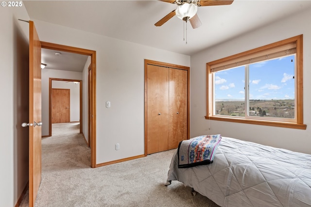 bedroom with light carpet, baseboards, a closet, and a ceiling fan