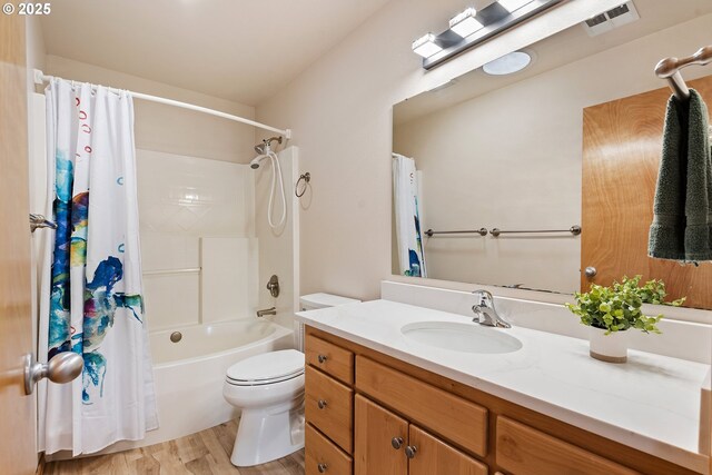 bathroom with vanity, shower / tub combo with curtain, toilet, visible vents, and wood finished floors