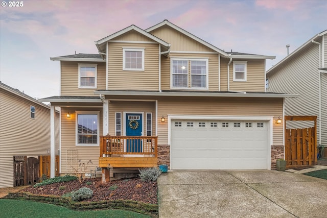 view of front facade with driveway, stone siding, an attached garage, and fence