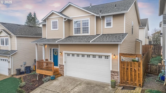 view of front facade featuring a garage, driveway, stone siding, roof with shingles, and fence