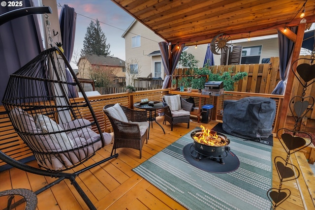 deck at dusk featuring a fire pit and grilling area