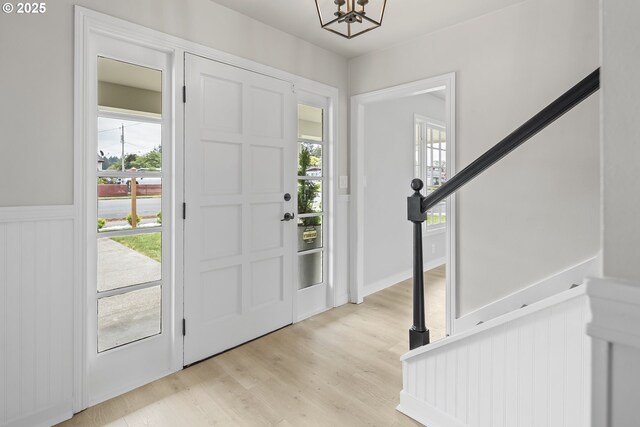 1061 NE Avery St, Newport, OR 97365 - foyer featuring a chandelier, light wood-type flooring, healthy amount of natural light, wainscoting, and stairs