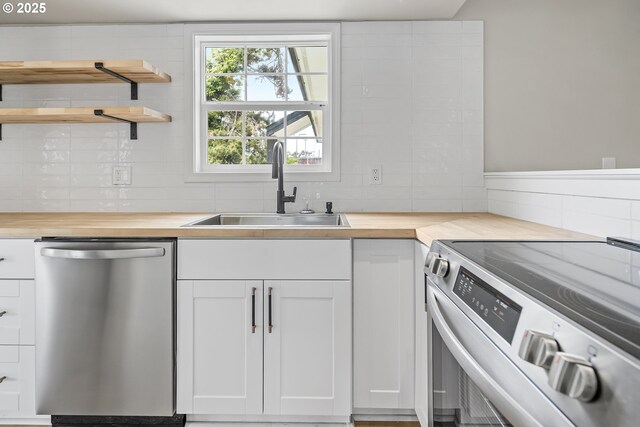 1061 NE Avery St, Newport, OR 97365 - kitchen with appliances with stainless steel finishes, wood counters, a sink, white cabinets, and tasteful backsplash