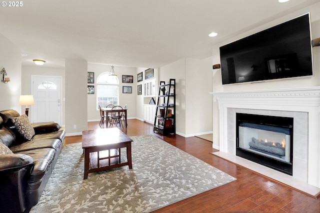 living room with baseboards, recessed lighting, wood finished floors, and a tiled fireplace