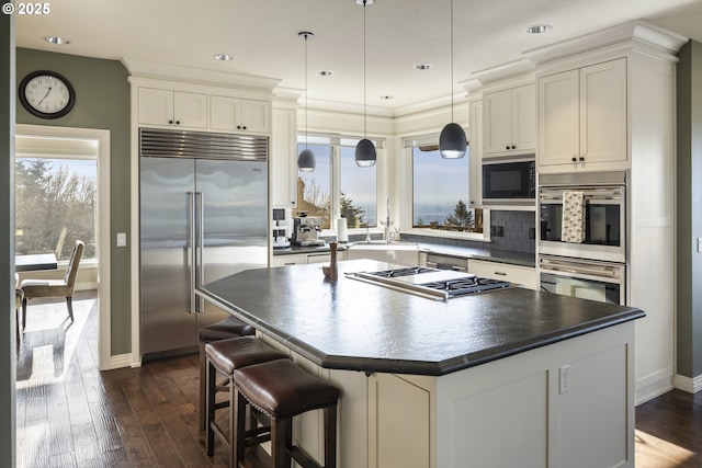 kitchen with backsplash, built in appliances, a center island, and decorative light fixtures