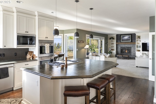 kitchen with white cabinetry, a kitchen island, a kitchen breakfast bar, and appliances with stainless steel finishes