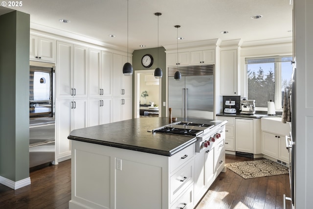 kitchen with hanging light fixtures, a kitchen island, white cabinets, and appliances with stainless steel finishes