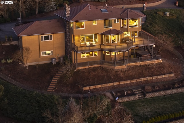 back house at night with cooling unit and a patio area