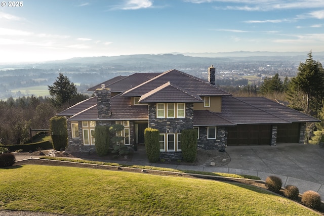 view of front of house featuring a mountain view, a garage, and a front lawn