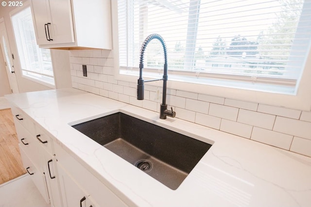 2797 Tulip St, Eugene, OR 97408 - kitchen featuring a sink, backsplash, light stone counters, and white cabinets