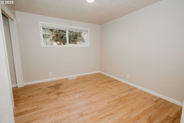 spare room featuring light wood-style floors and baseboards