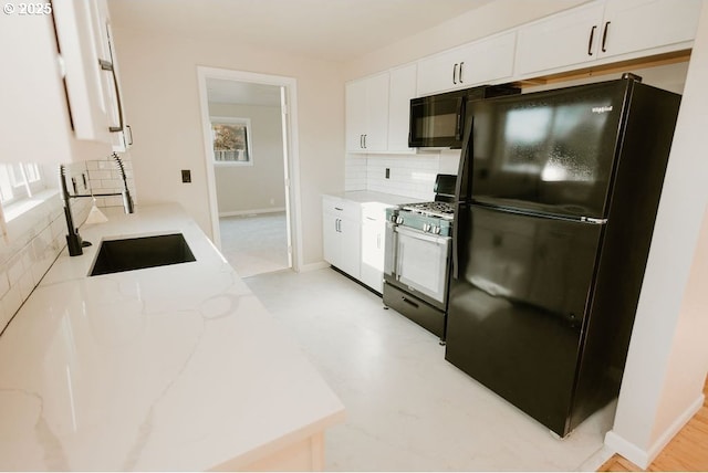 kitchen featuring black appliances, white cabinetry, tasteful backsplash, and a sink