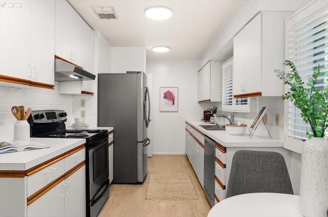 2425 SW 19th Ave Unit 9, Portland, OR 97201 - kitchen featuring appliances with stainless steel finishes, under cabinet range hood, white cabinets, and light wood-style floors