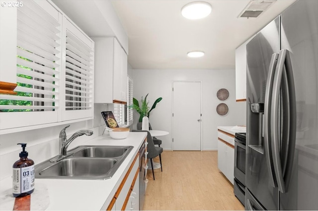 2425 SW 19th Ave Unit 9, Portland, OR 97201 - kitchen with stainless steel refrigerator with ice dispenser, white cabinets, light wood-style floors, and light countertops