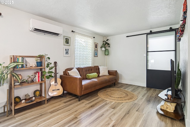 8626 SE 28th Pl, Milwaukie, OR 97222 - living room with a wall mounted AC, a textured ceiling, light wood finished floors, a barn door, and baseboards
