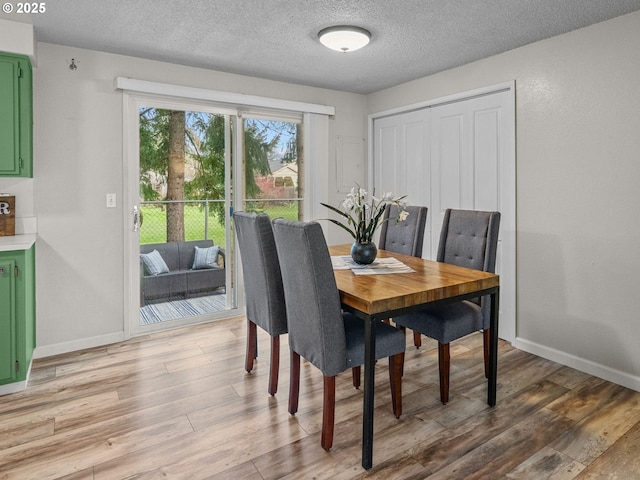 dining area with a textured ceiling and light wood-type flooring