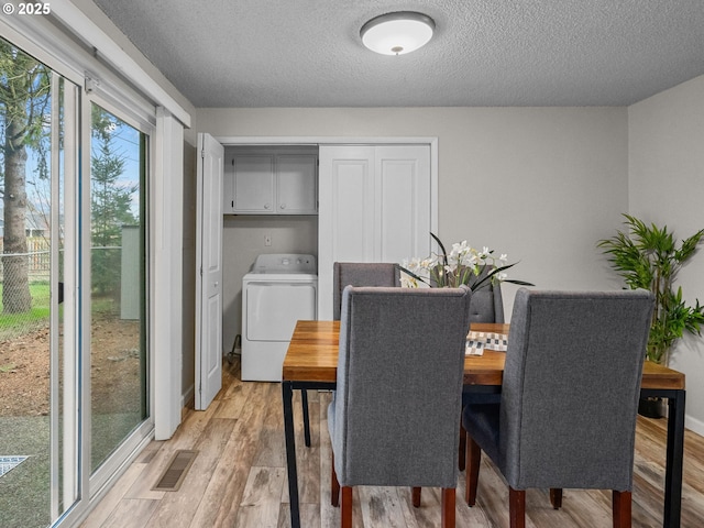 dining area with washer / clothes dryer, a textured ceiling, and light wood-type flooring