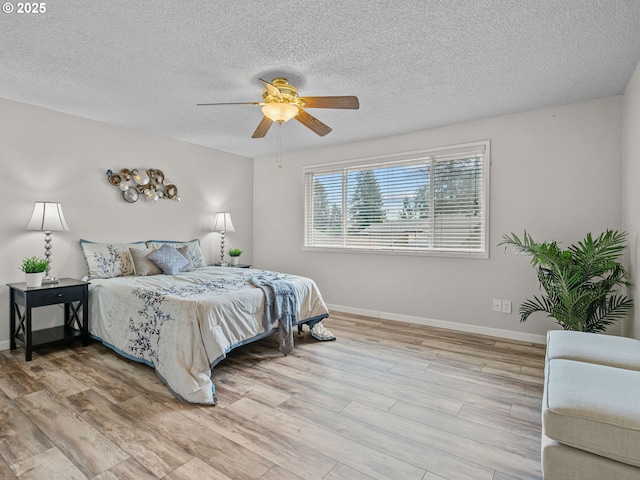 bedroom with ceiling fan, light hardwood / wood-style floors, and a textured ceiling