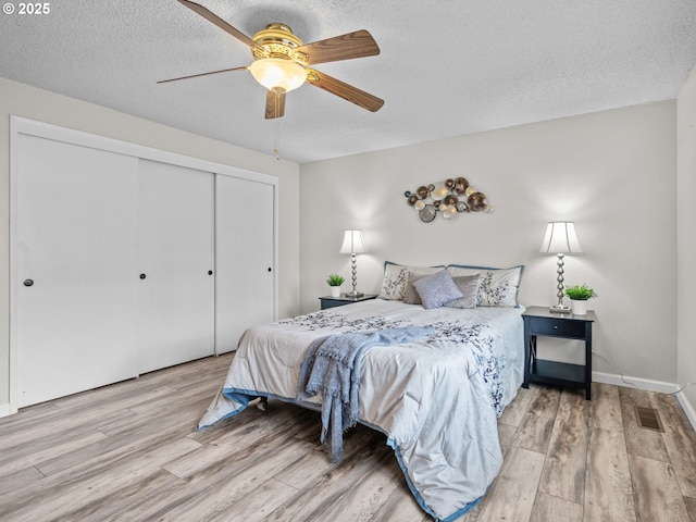 bedroom with ceiling fan, a closet, a textured ceiling, and light wood-type flooring