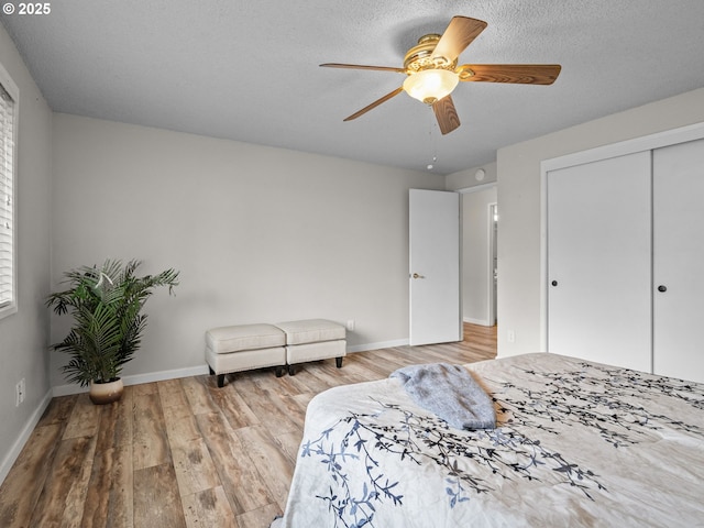 bedroom featuring ceiling fan, a closet, a textured ceiling, and light wood-type flooring