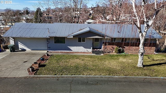 ranch-style home with an attached garage, concrete driveway, metal roof, and a front yard