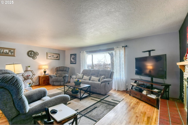 living room featuring a textured ceiling, wood-type flooring, and a fireplace