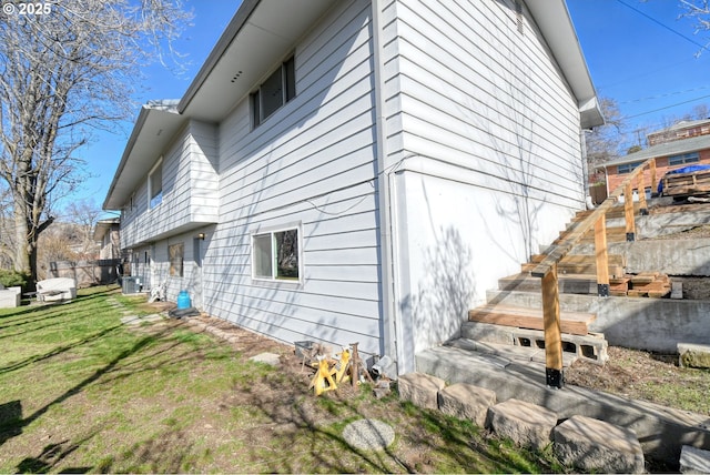 view of property exterior with a yard and stairway