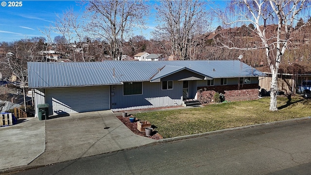 ranch-style home featuring an attached garage, driveway, metal roof, and a front yard